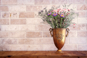 bouquet of colorful field flowers in the antique bronze vase over wooden table
