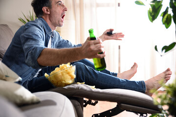 Angry man watching sports on television sitting on sofa