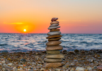 Pyramid of stones on pebble beach at sunset