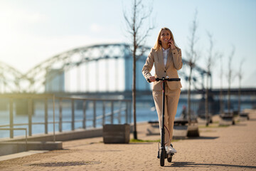 Woman riding on electric scooter and talking on phone © Kaspars Grinvalds