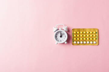 World sexual health or Aids day, Top view flat lay medicine birth control, alarm clock and contraceptive pills, studio shot isolated on a pink background, Safe sex and reproductive health concept