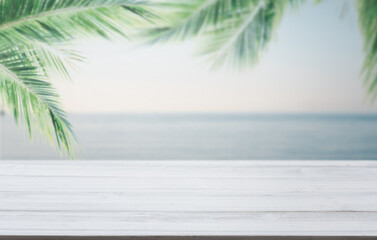 White wooden planks with blur beach sky on background and  palm leaves on foreground,summer concepts.