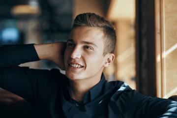 Handsome guy in a dark shirt at a table in a cafe restaurant sunlight model