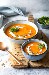 Vegetarian autumn pumpkin and carrot soup with cream, seeds and cilantro micro greens. Comfort...