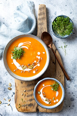 Vegetarian autumn pumpkin and carrot soup with cream, seeds and cilantro micro greens. Comfort food, fall and winter healthy slow food concept