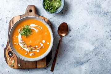 Vegetarian autumn pumpkin and carrot soup with cream, seeds and cilantro micro greens. Comfort...