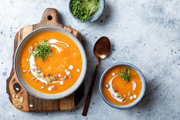 Vegetarian autumn pumpkin and carrot soup with cream, seeds and cilantro micro greens. Comfort...