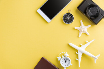 World Tourism Day, Top view of minimal model plane, airplane, starfish, alarm clock, compass and smartphone blank screen, studio shot isolated on yellow background, accessory flight holiday concept