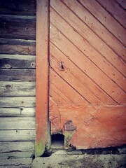 Old wooden door with an old bolt and lock, and an entrance for a pet cat.