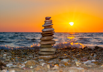 Pyramid of stones on pebble beach at sunset