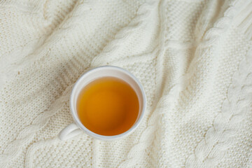 A mug of hot tea on a knitted blanket. Cozy autumn. Winter breakfast.