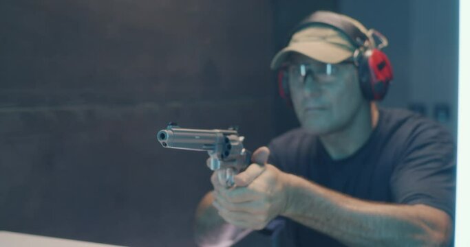 Mature man firing revolver in shooting range