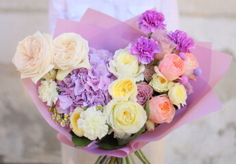 Colorful flowers assorted bouquet in color paper. Holiday celebration concept. Bouquet of beautiful flowers in hands. Colorful flowers bouquet wrapped in paper