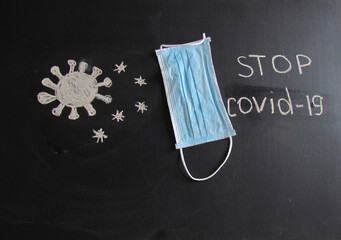 The inscription on the board "Stop Covid-19". Mask on the board