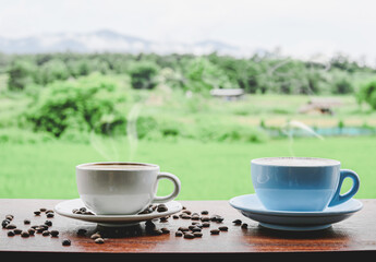 Two coffee cups on the wooden table with green nature background