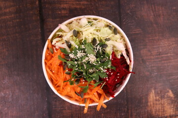 Delicious mixed salad with seeds, red beets, carrots and cabbage on the wooden table
