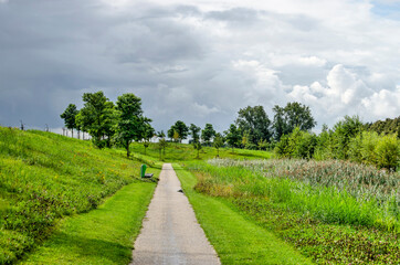 Fototapeta na wymiar Dramatic sky with approaching rain clouds over a footpath in the new Annie M.G. Schmidt Park in Berkel en Rodenrijs, The Netherlands