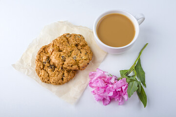 Coffee or tea with milk and oat cookies. Romantic vintage still life with snack and pink flowers in spring, summer day