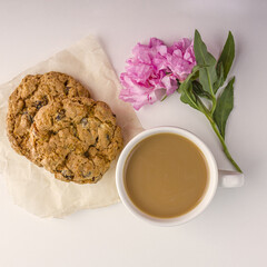 Coffee or tea with milk and oat cookies. Romantic vintage still life with snack and pink flowers in spring, summer day