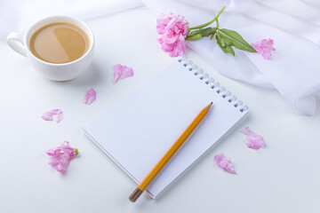 Flat lay flowers romantic still life. Morning coffee mug for breakfast, empty notebook with copy space for text or challenge today and pink flowers. Freelancer woman workplace