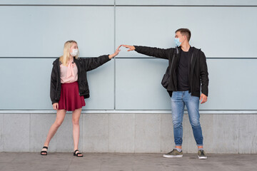 Fototapeta premium Young, happy, loving couple wearing masks and holding hands with the social distance