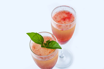 Cooling Rossini italian alcoholic cocktail with sparkling wine, strawberry puree, ice cubes in champagne glass. Refreshing summer lemonade or ice tea served with mint leaves