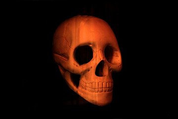 Orange halloween skull sculpture over black wallpaper