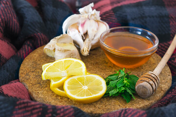 home treatment kit for flu and seasonal colds. Lemon, mint, honey, ginger and garlic on wooden tray on scarf