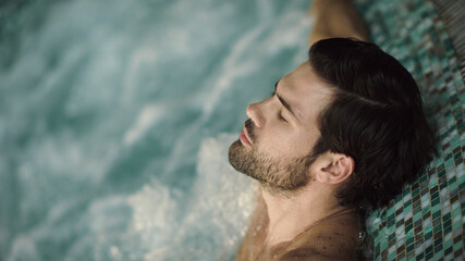 Closeup sexy man enjoying jacuzzi spa. Portrait of handsome guy relaxing in pool - obrazy, fototapety, plakaty