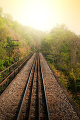 Railroad passing ancient steel bridge over a gorge.