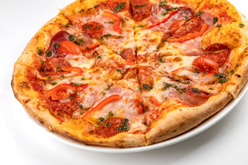 pizza with ham, sausage and tomatoes on a white plate