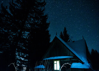 Wooden house in night winter mountain forest