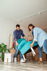 Couple carrying armchair while moving in new home