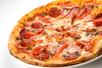 pizza with ham, sausage and tomatoes on a white plate