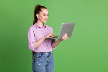 Profile side photo of positive manager girl work remote laptop have wifi connection social networking communication wear lilac violet denim jeans isolated green color background