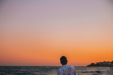 Silhouette of a man on the beach looking at sunset