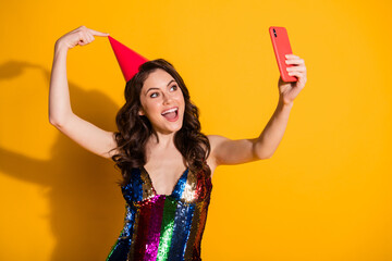 Photo of amazed girl blogger influencer take selfie smartphone point finger her red headwear cone wear rainbow glossy skirt isolated over bright shine color background