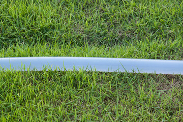 watering hose is an agricultural accessory on a green lawn in the backyard.