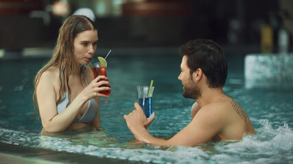 Young couple relaxing at whirlpool indoor. Attractive couple drinking cocktails