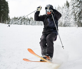 Man skier in black ski suit and goggles skiing downhill trough deep powder snow. Young man...