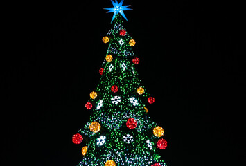 festive christmas tree with lights, balls and star isolated on black 