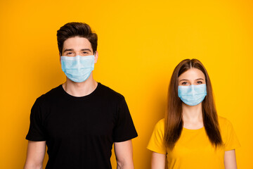 Portrait of her she his he nice attractive couple standing side by side wearing gauze mask preventive measures contamination social distance isolated bright vivid shine vibrant yellow color background