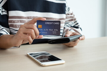 The businesswoman's hand is holding a credit card and using a smartphone for online shopping and internet payment in the office