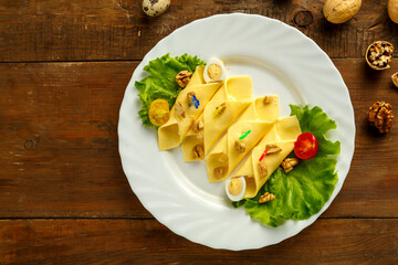 Cheese rolls on a plate with green salad near eggs on a wooden table. save a place.