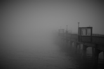 Pier in fog, black and white