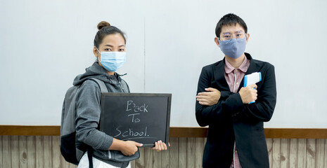 Back to school. Asian male teacher using thermometer temperature screening student for fever against the spread of COVID-19 Before entering the classroom. Virus protection concept