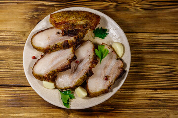 Baked pork belly in a plate on wooden table. Top view