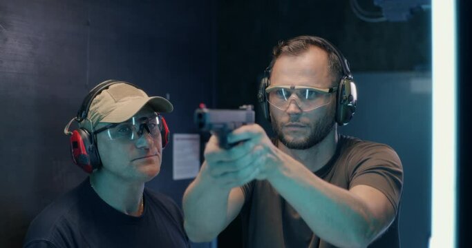Mature instructor teaching man to shoot pistol