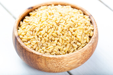 Raw uncooked bulgur wheat grains in a bowl close up