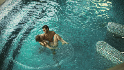 Top view of happy couple enjoying pool. Joyful couple relaxing at wellness hotel